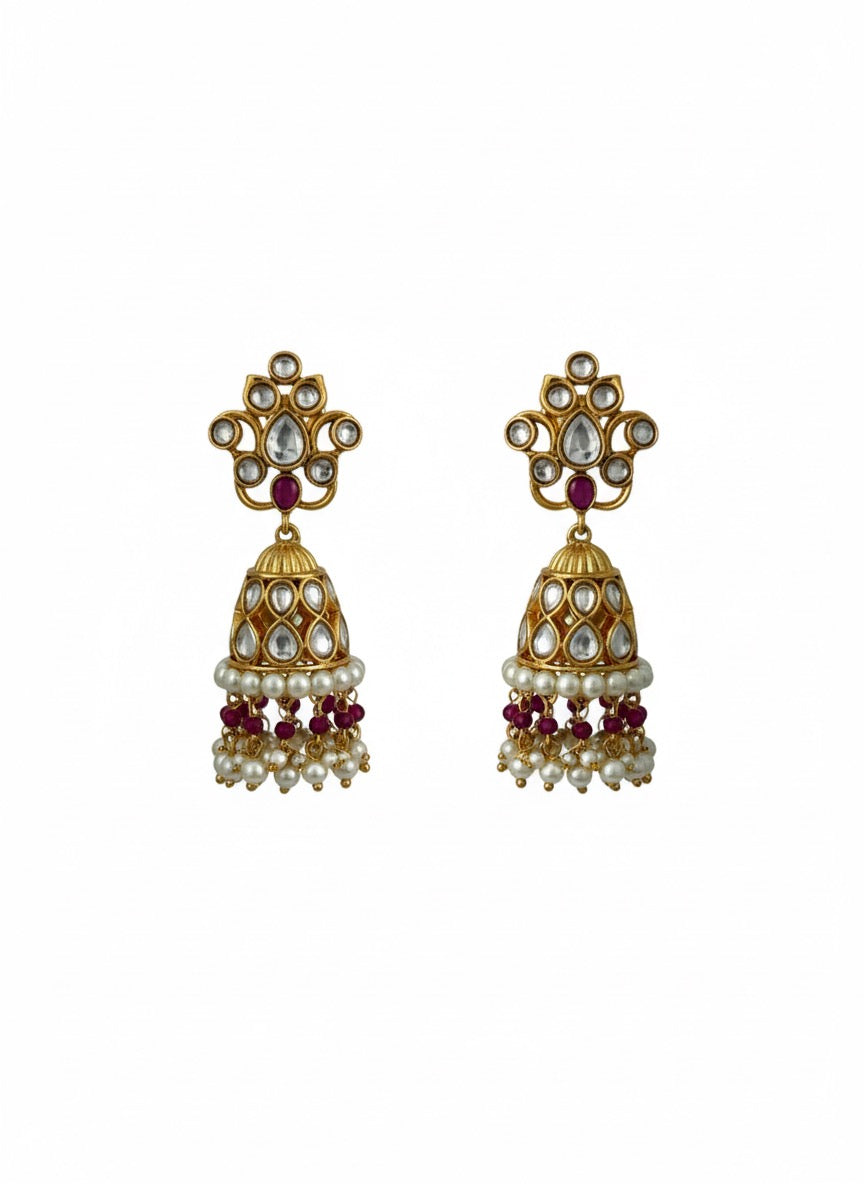 Gold plated Kundan Jhumka earrings featuring white Polki stones, a floral stud, and hanging clusters of ruby red and white pearl beads.